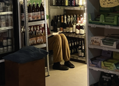 Das Foto zeigt eine Person, die ein Buch auf den Knien hat und in einer Ecke im Mila-O Laden in Kaufungen sitzt.