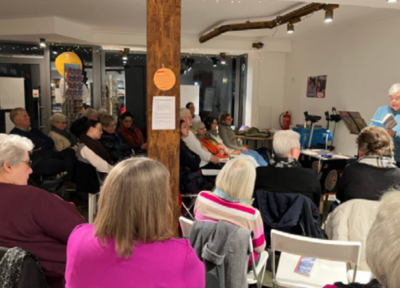 Das Bild zeigt eine Buchlesung und Gäste im Publikum