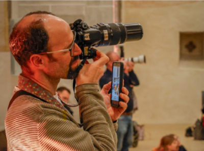 Das Bild zeigt einen Mann mit Kamera vor dem Auge