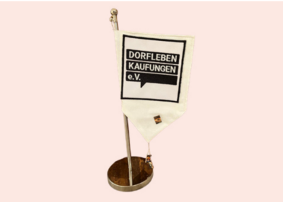 Das Bild zeigt eine kleine Fahne mit dem Dorfleben Logo