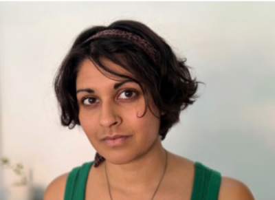 Das Bild zeigt eine Frau mit mittellangen dunkeln Haaren die direkt in die Kamera blickt.